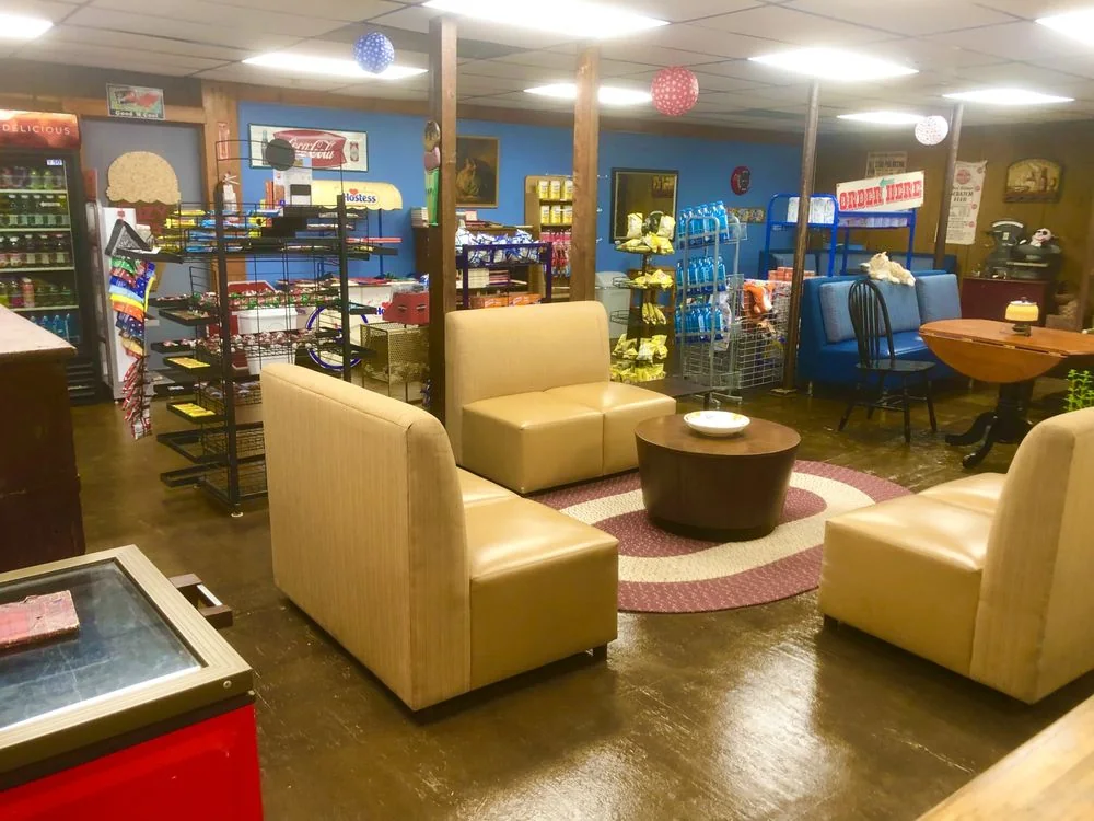 The lounge inside the store with leather chairs, a rug and shelves of goods