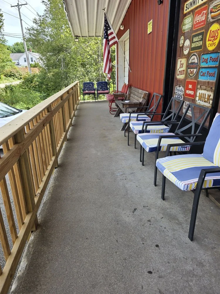 The front porch of Suzy Q's Summit General with rocking chairs, an American flag and old tin signs